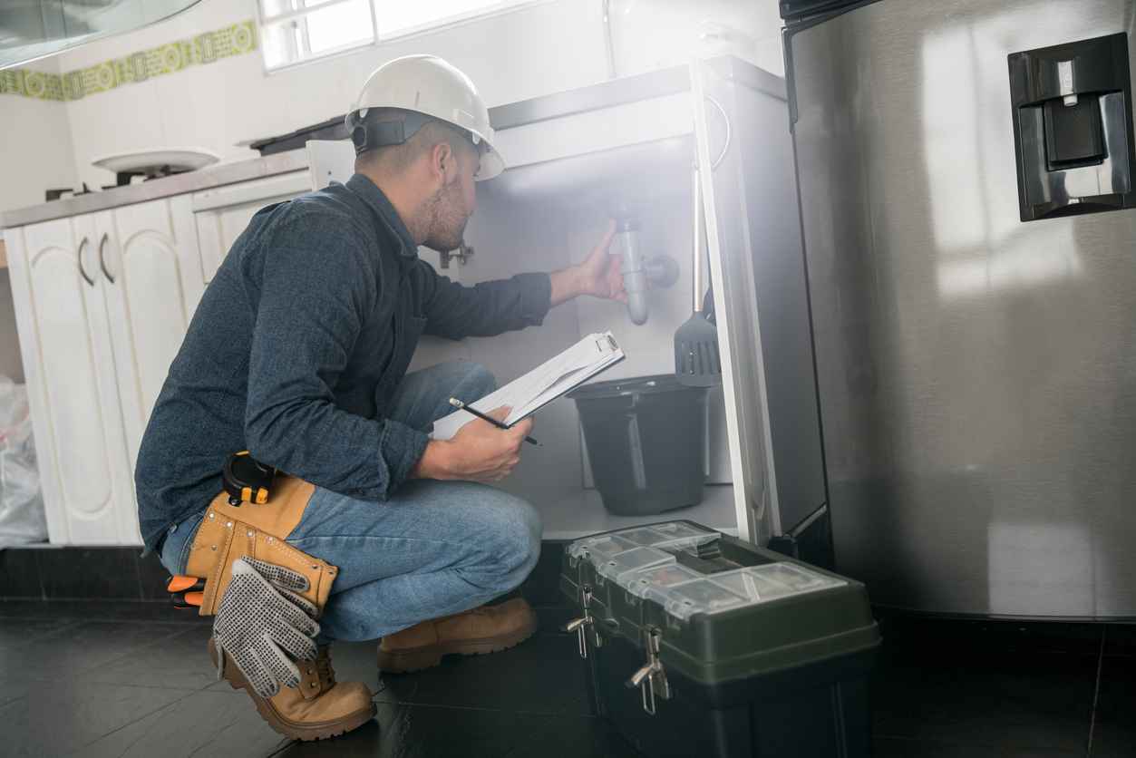 Plumber fixing a leak problem with the sink in the kitchen