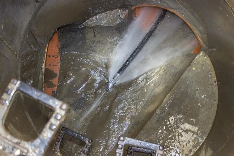 High-pressure water jet cleaning a clogged sewer pipe